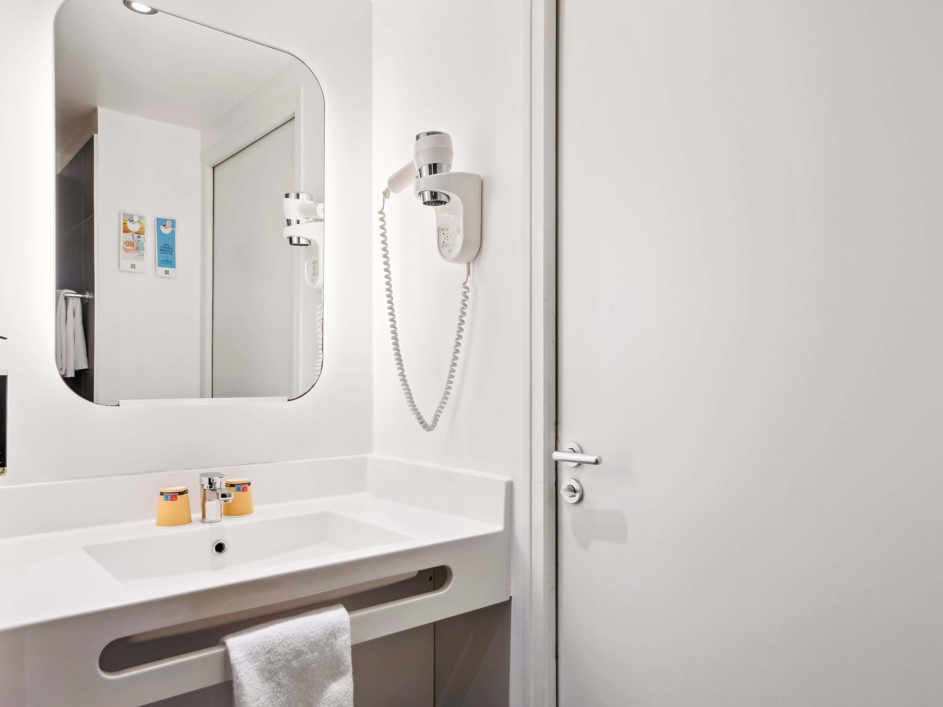 A bathroom with a white sink, a mirror, a hairdryer, and a towel rack.