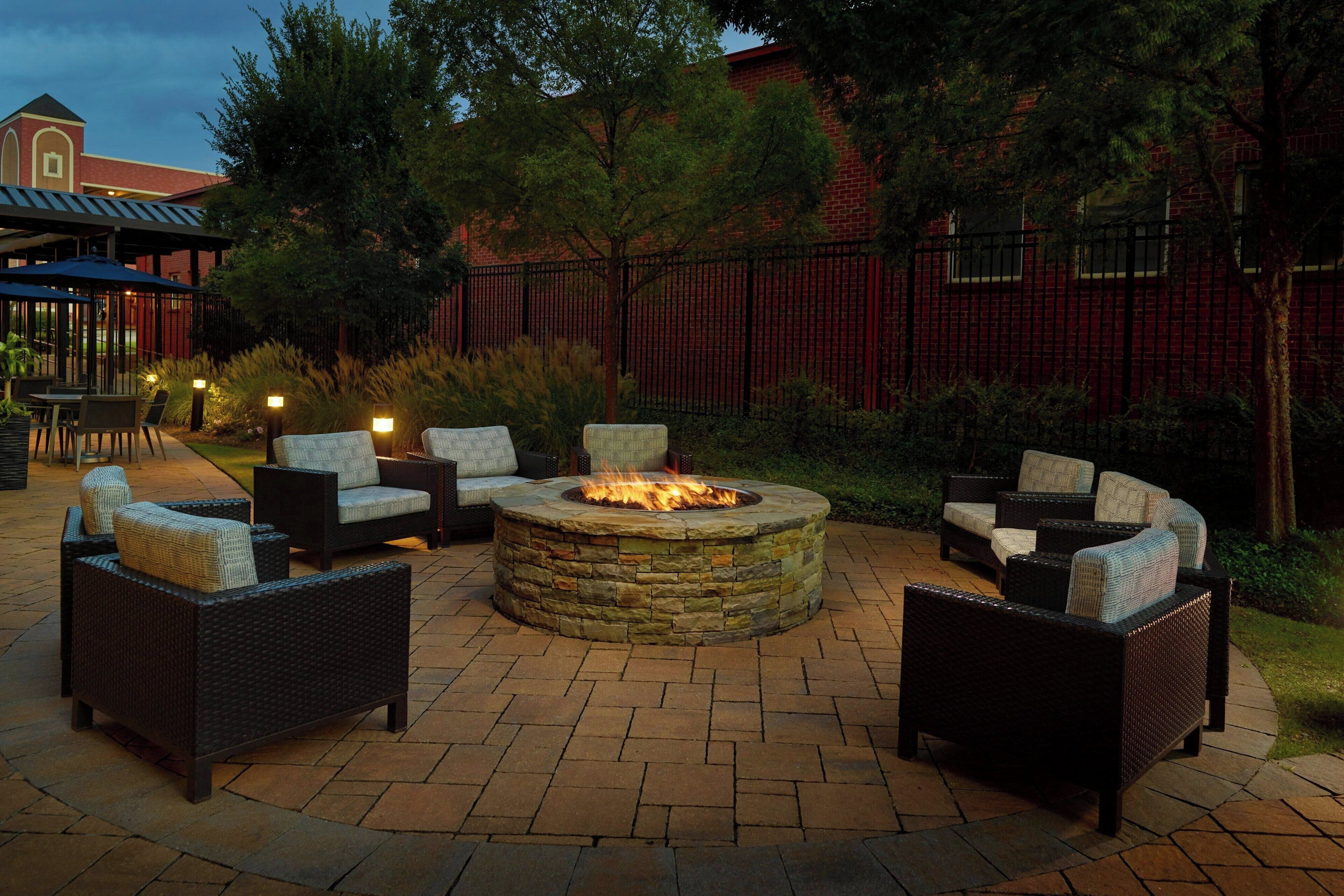 An outdoor patio area with a stone fire pit surrounded by wicker furniture.