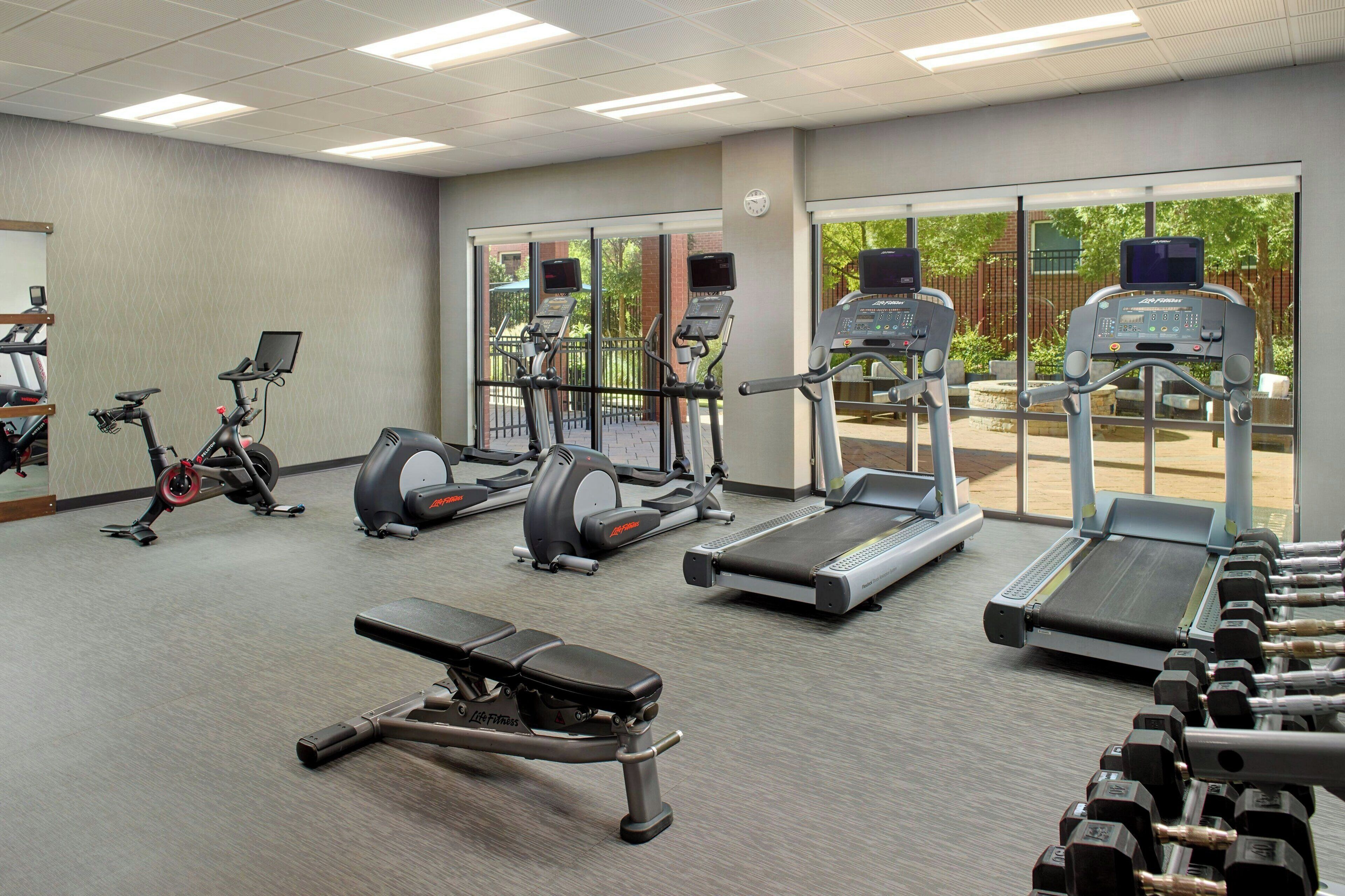 Un gimnasio con cintas de correr, elípticas y mancuernas.