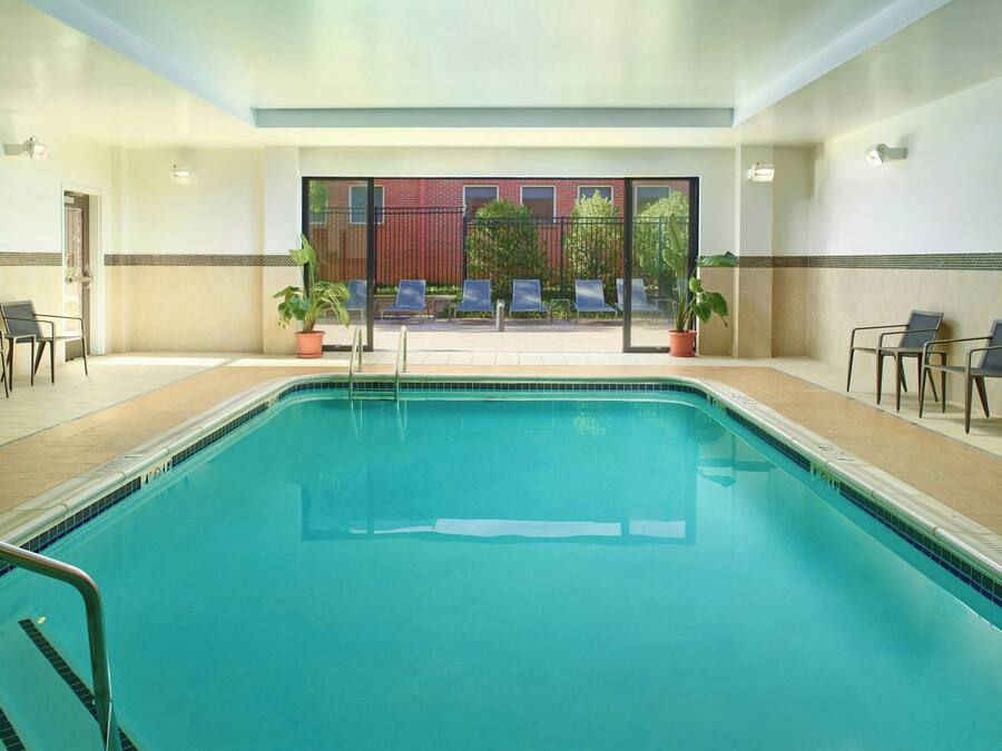 Una piscina con sillones de descanso y plantas en macetas.