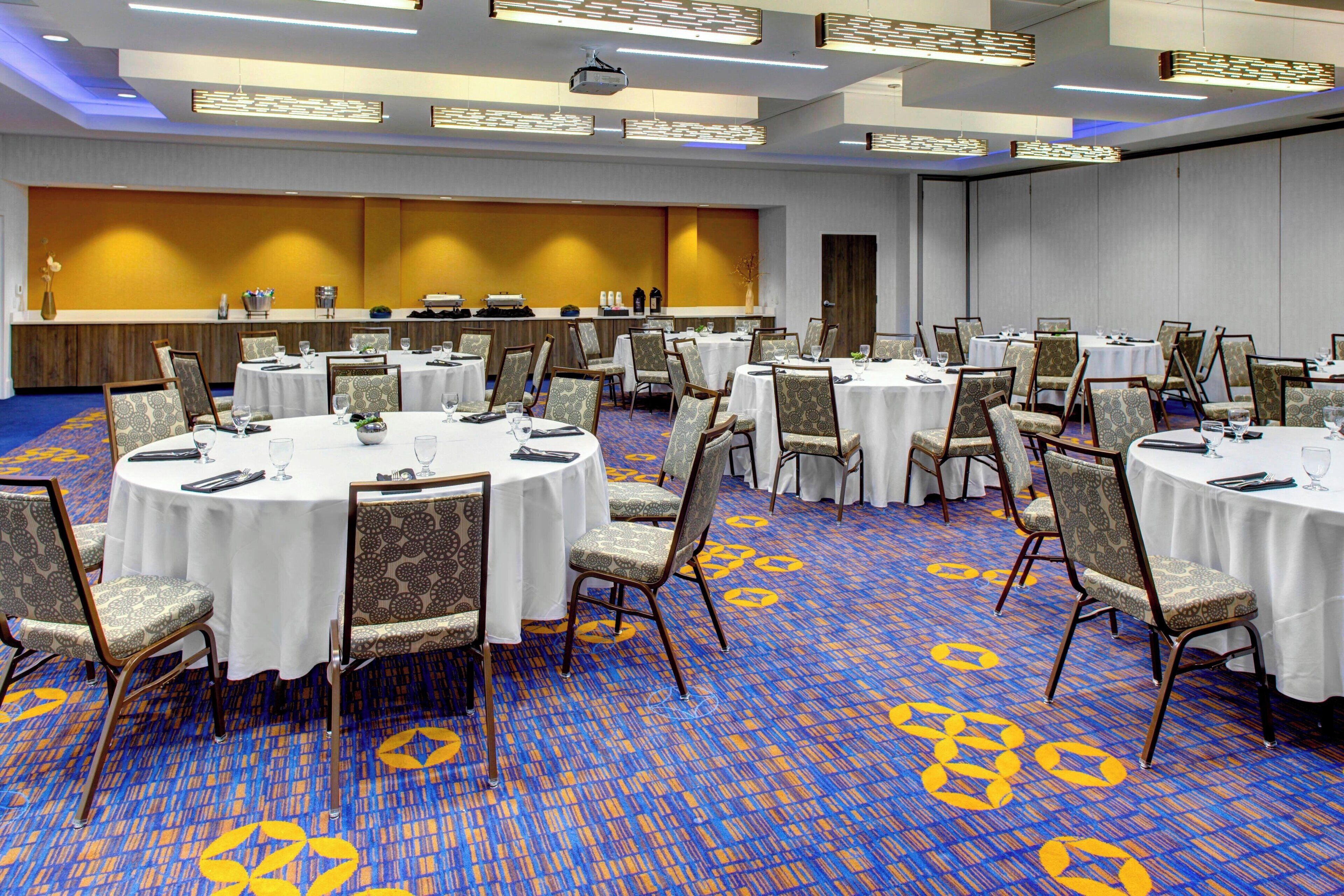 A conference room with round tables, chairs, and a carpeted floor.