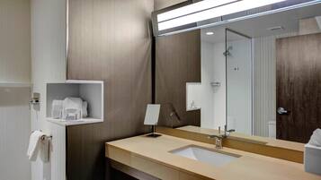 A modern bathroom with a large mirror, a sink, and a towel rack.