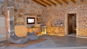 A stone-walled room with a wooden ceiling, a small table with a potted plant, and two bean bags. - Agroturismo Petit Hotel Son Perdiu - Adults Only (Llucmajor)