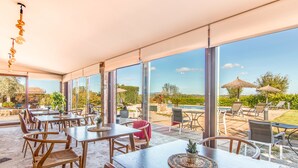 A spacious patio area with outdoor seating and large windows offering a view of the landscape. - Agroturismo Petit Hotel Son Perdiu - Adults Only (Llucmajor)