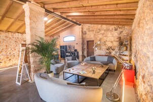 Una habitación rústica con paredes de piedra y techo de madera, amueblada con sofás, una mesa de centro y una lámpara de pie.