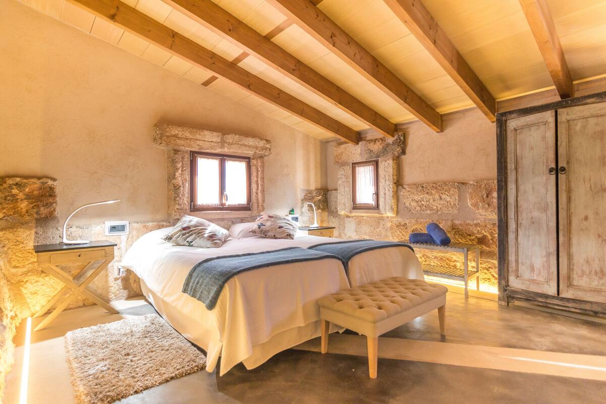 Une chambre à coucher avec un grand lit, un banc, un bureau et une armoire.