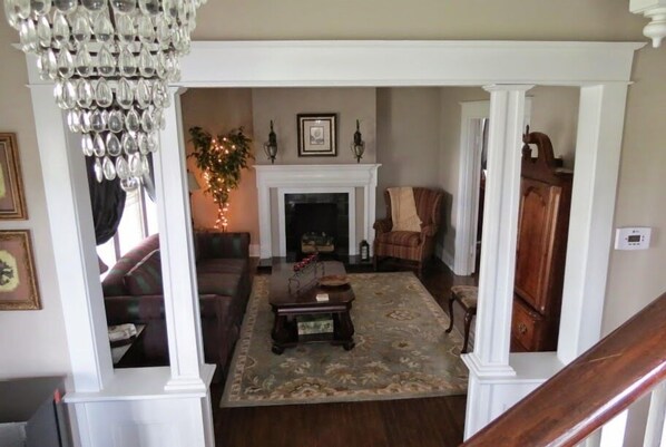 A living room with a fireplace, a chandelier, and a large wooden cabinet.