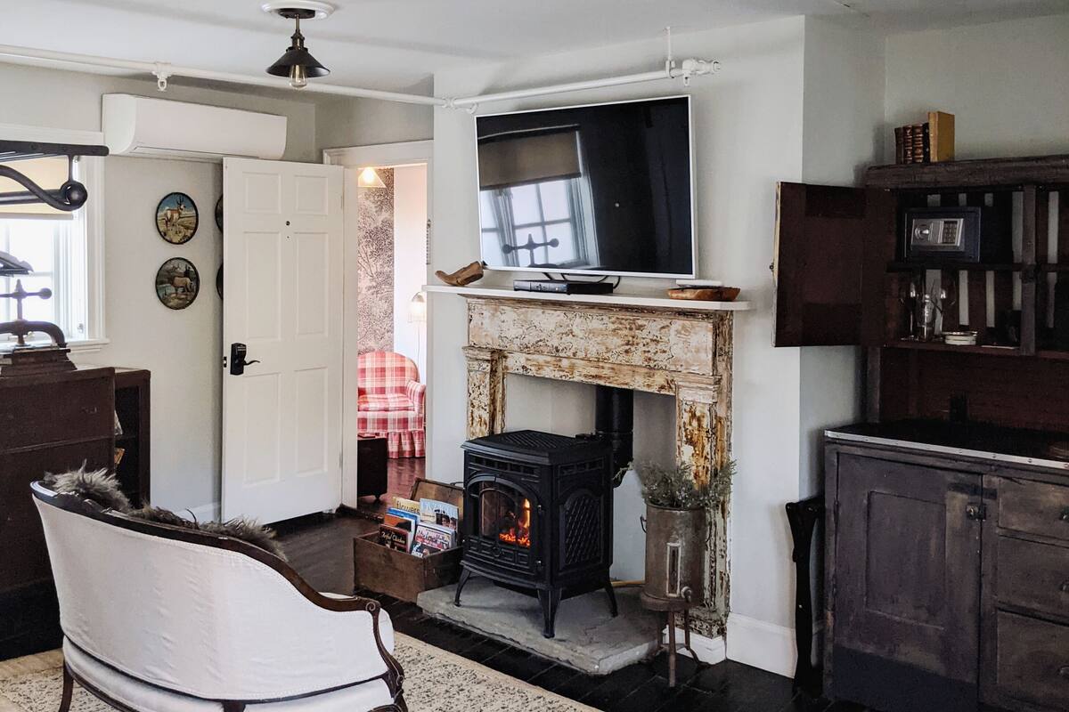 A living room with a fireplace, a television, and a ceiling fan.
