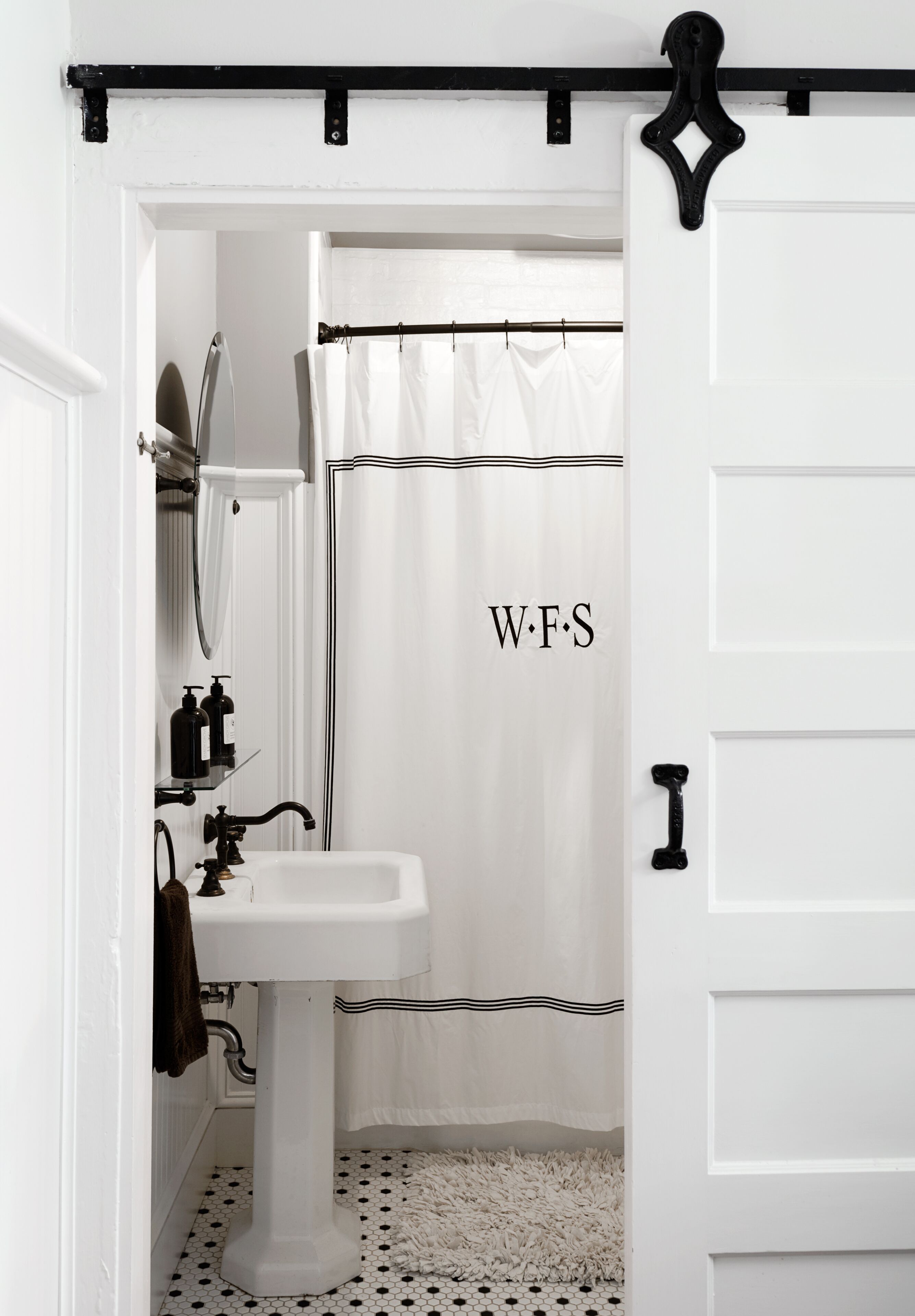 A bathroom with a white sink, a mirror, and a shower curtain with "W.F.S" on it.