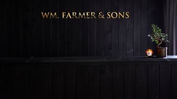 WM. FARMER & SONS sign adorns a minimalist interior, complemented by a potted plant and a CLARY SAGE candle.