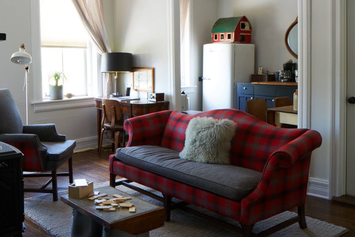 A living room with a red plaid sofa, a wooden coffee table, and a small bookshelf.