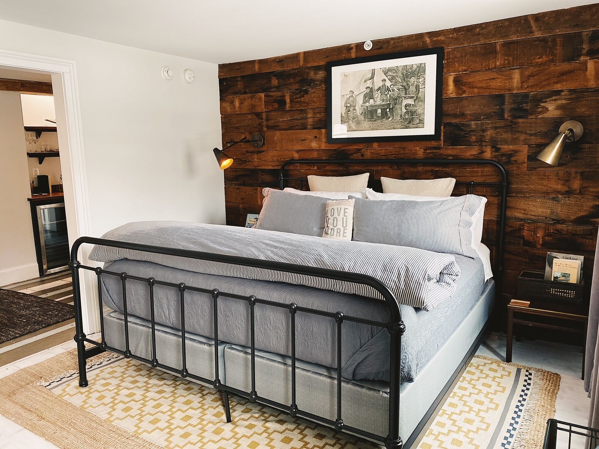 A bed with a metal frame, a wooden wall, and a framed picture above it.