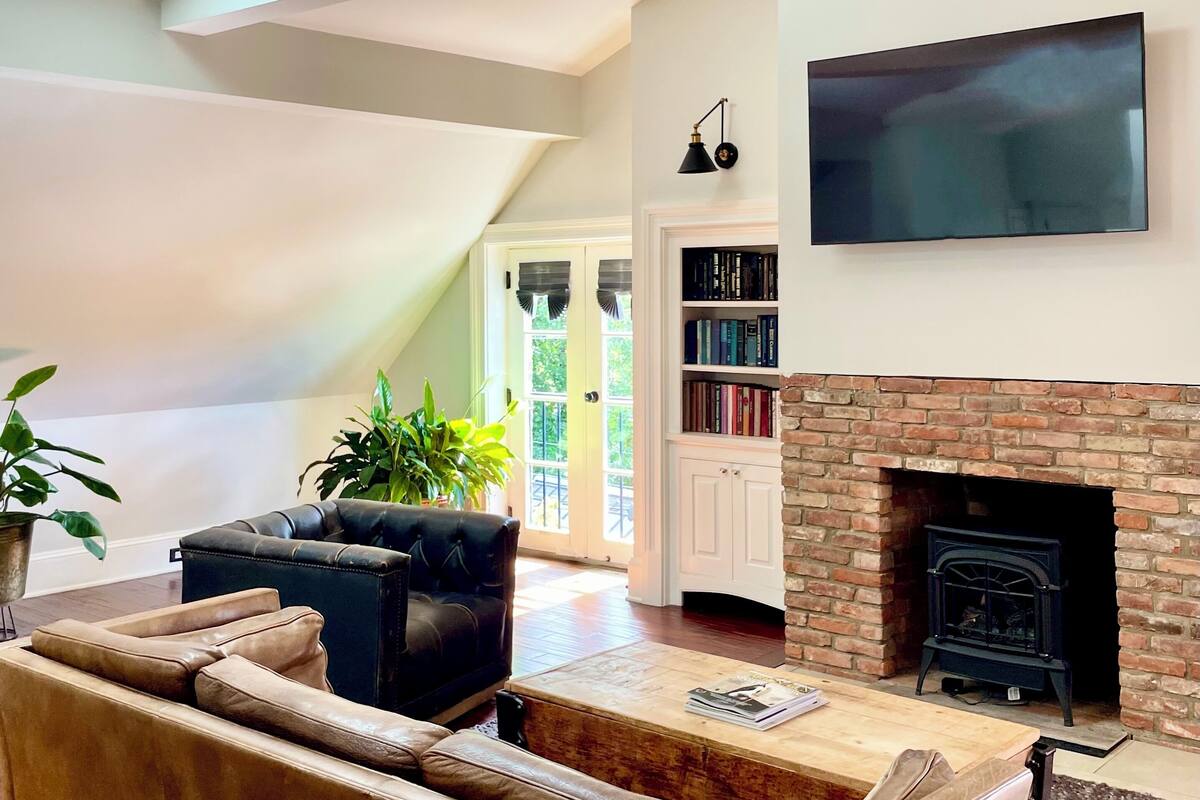 A living room with a sofa, a fireplace, a TV, and a bookshelf.