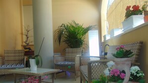 Un espace de détente intérieur, chaleureux, avec des meubles en osier, une plante en pot et des pots en terre cuite ornés de fleurs.