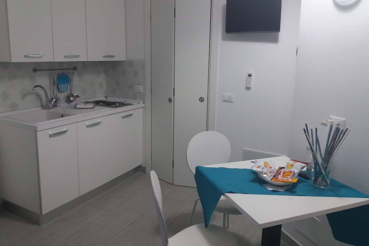 A compact kitchen with white cabinets, a built-in sink, and a small dining area with a table and chairs.