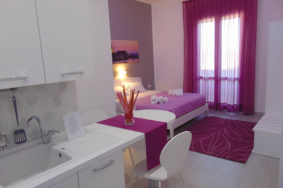 A modern hotel room with a bed, a desk, and a bathroom.
