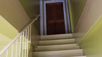 A staircase with a wooden door at the top, white railings, and a light-colored wall.