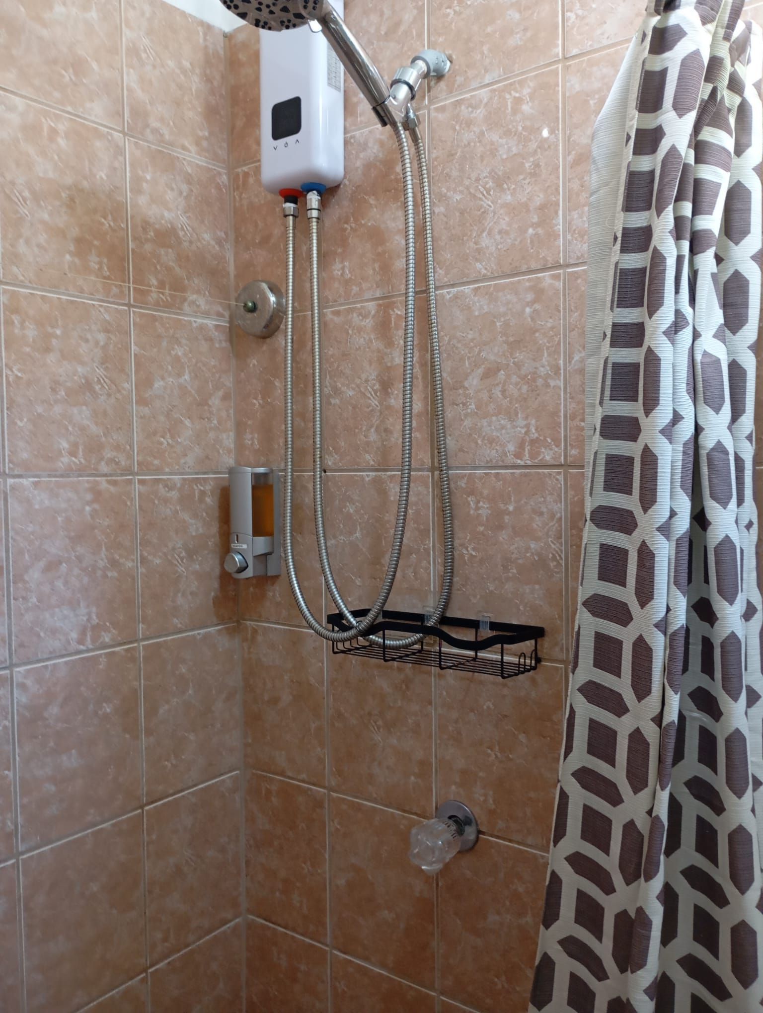 Una ducha con cabezal de ducha manual, un panel de control y un perchero para toallas.