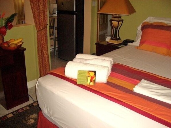 Una habitación de hotel con cama, mesita de noche, lámpara y frutero.