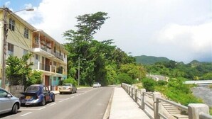A road with cars, a sidewalk, and a building with balconies.