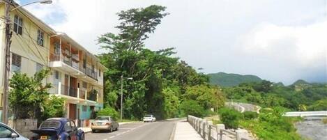 Una calle con autos, una acera y un edificio con balcones.