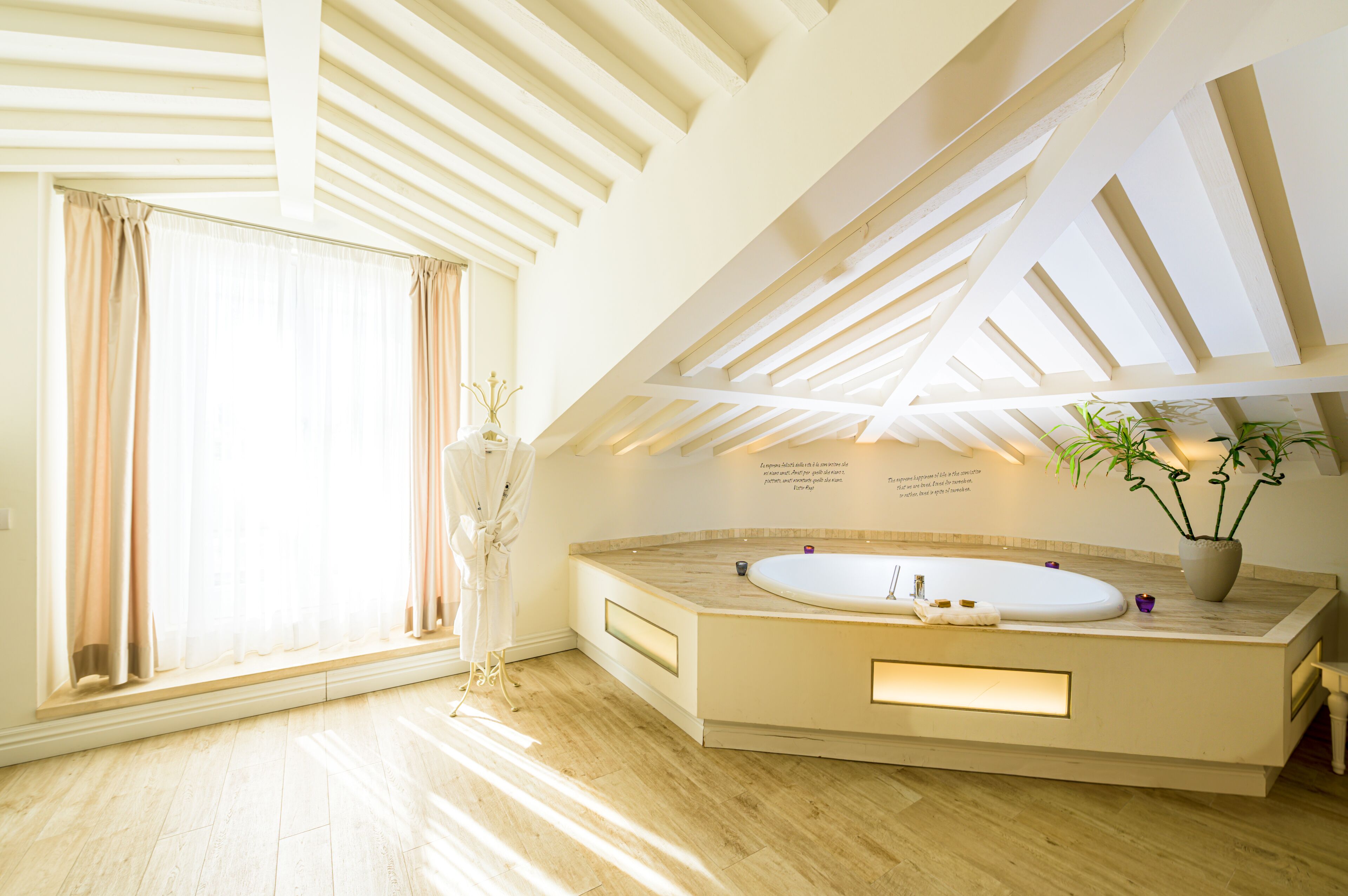 A modern bathroom with a freestanding bathtub, a large window with curtains, and a skylight.