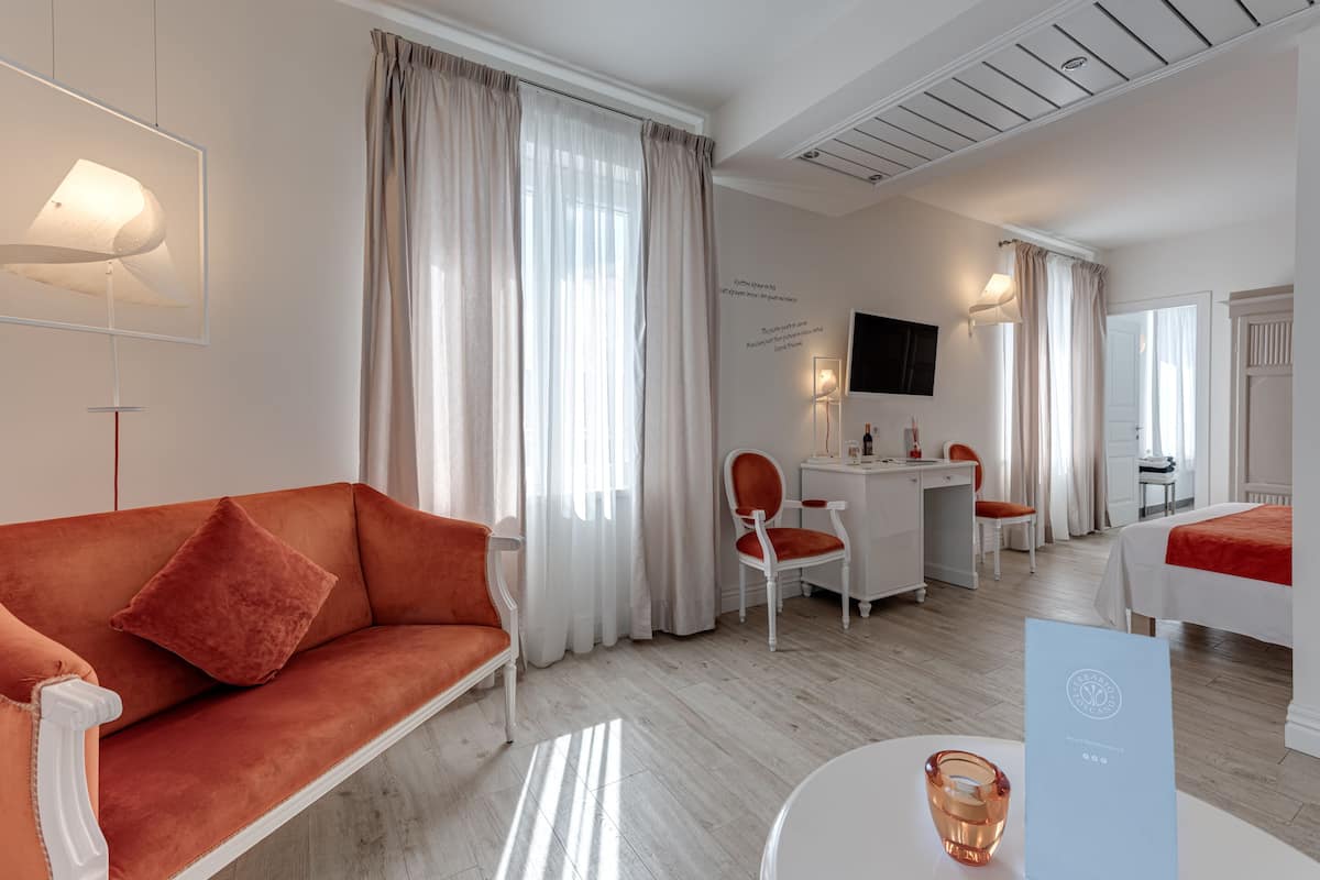 Una habitación de hotel moderna con sofá, escritorio, silla y cama.
