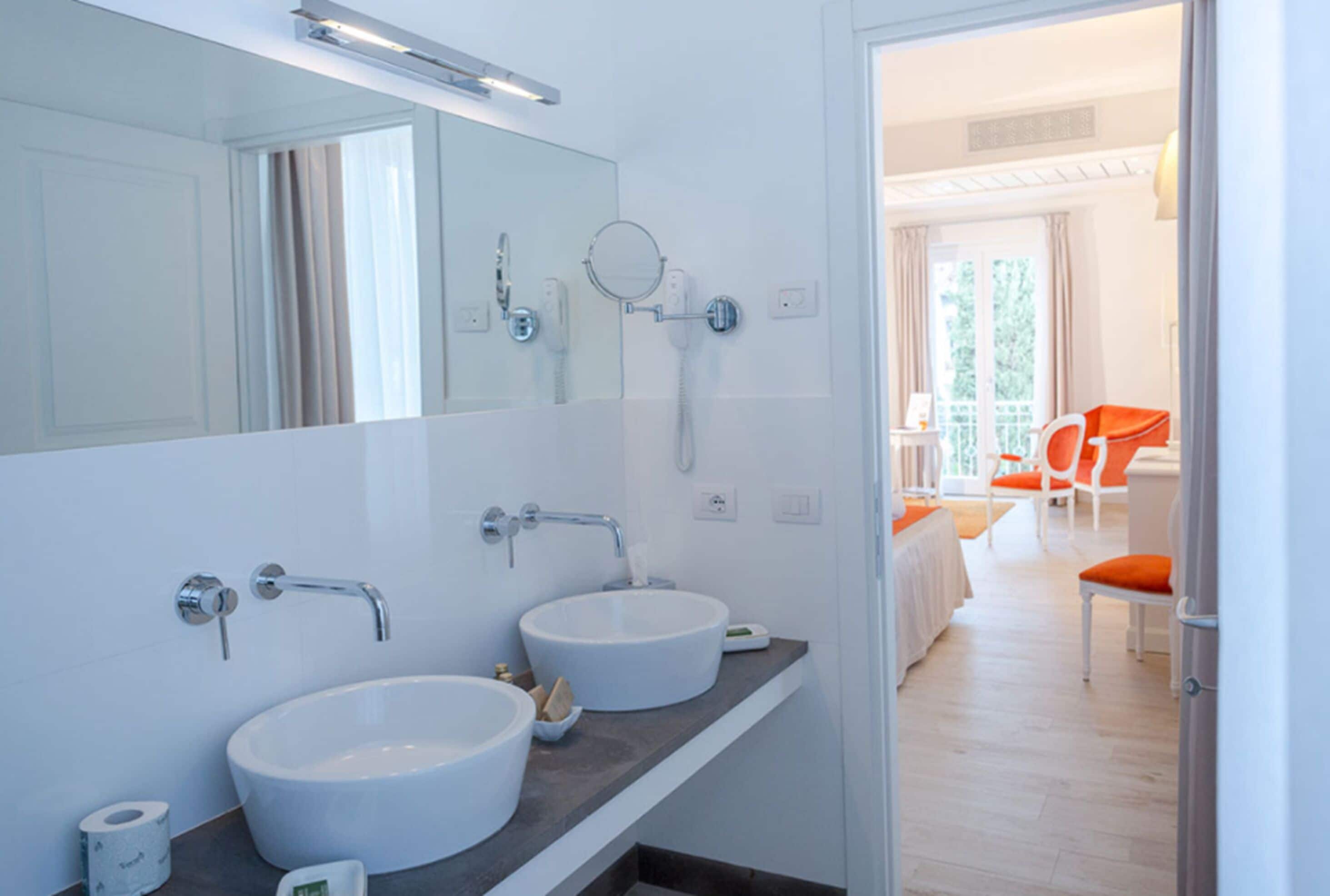 Ein modernes Badezimmer mit zwei Waschbecken, einem großen Spiegel und einer Duschkabine.