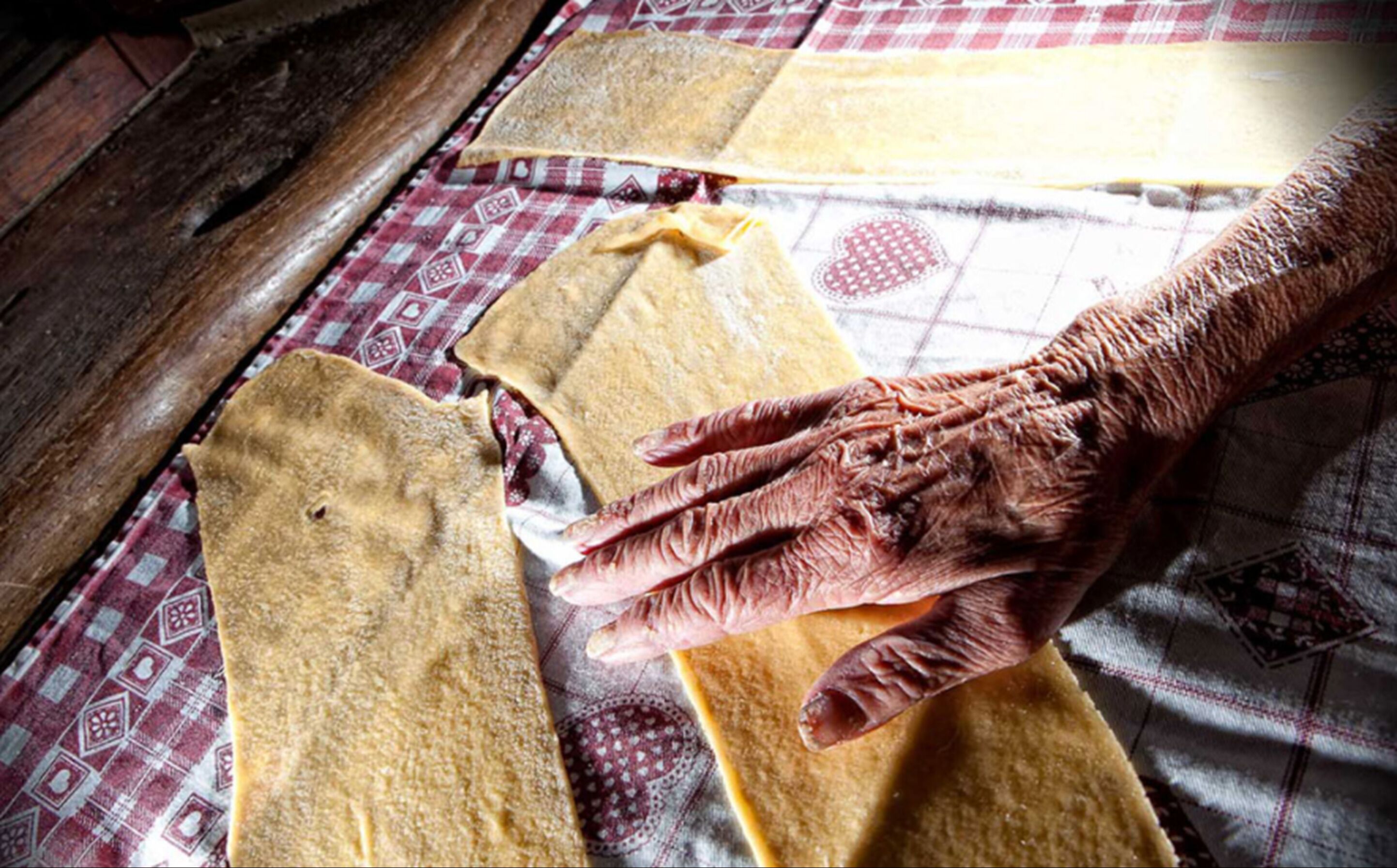 A hand pressing dough on a patterned cloth.