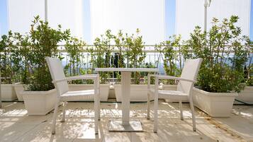 Un patio con mobiliario de mimbre blanco y plantas en macetas.