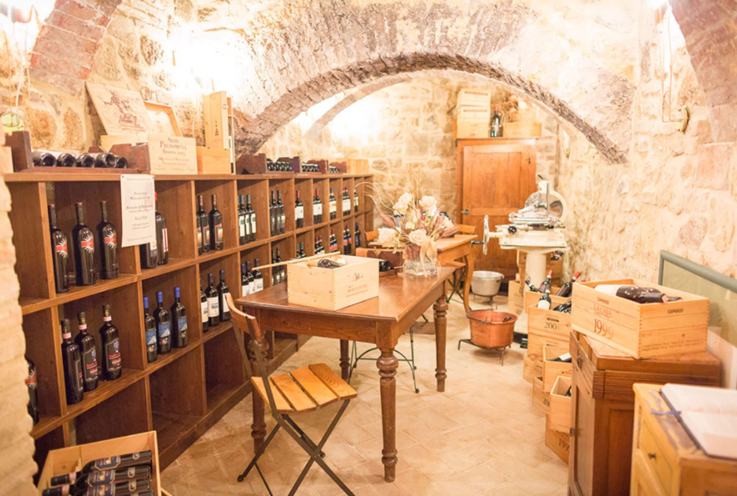 Una bodega con estantes y mesas de madera, llena de botellas y cajas de vino.