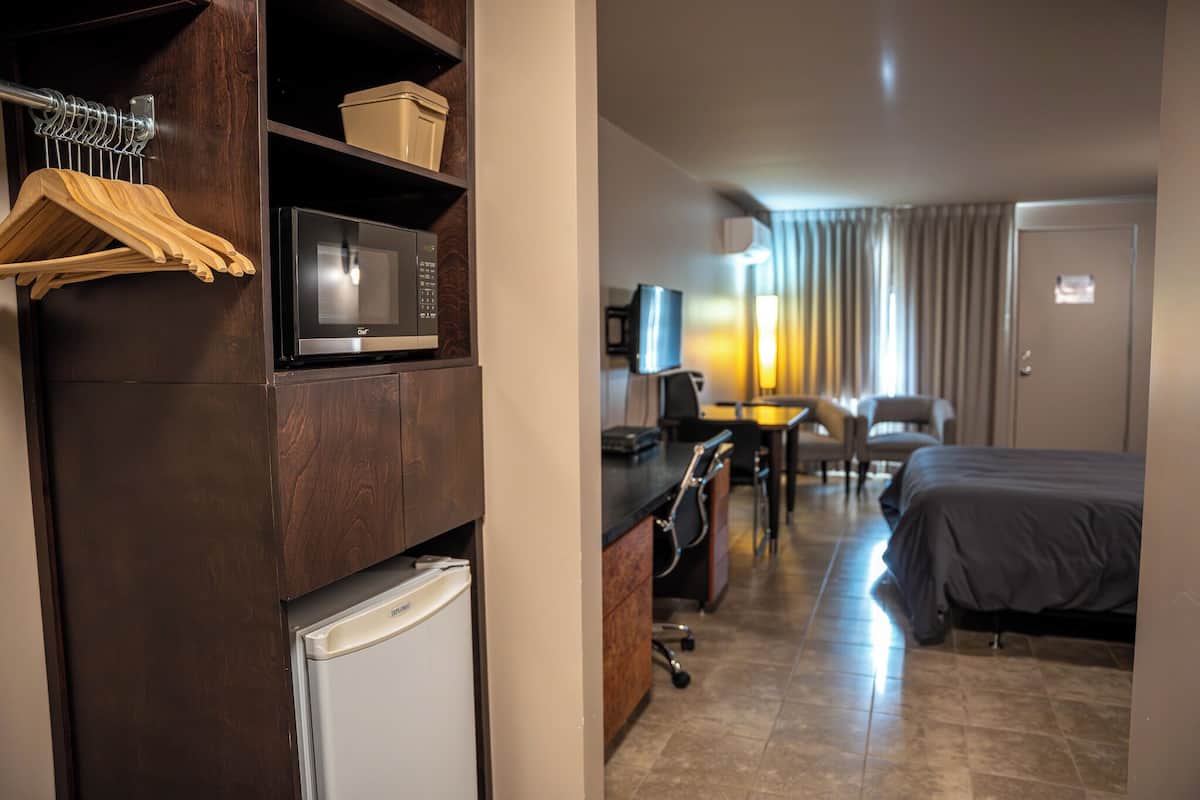 Une chambre d’hôtel équipée d’un lit, d’un bureau, d’une chaise, d’un four à micro-ondes et d’un petit réfrigérateur.
