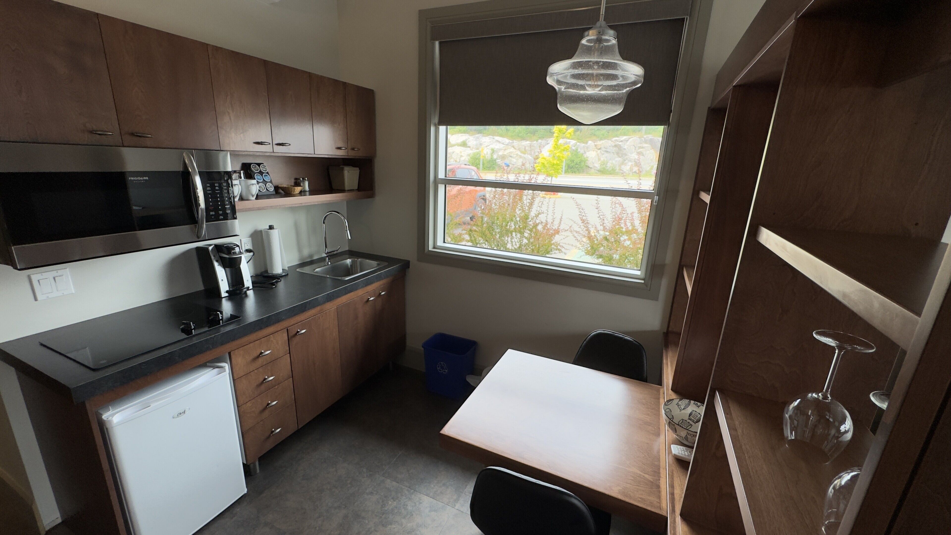 A compact kitchen with a refrigerator, microwave, coffee maker, and a sink.