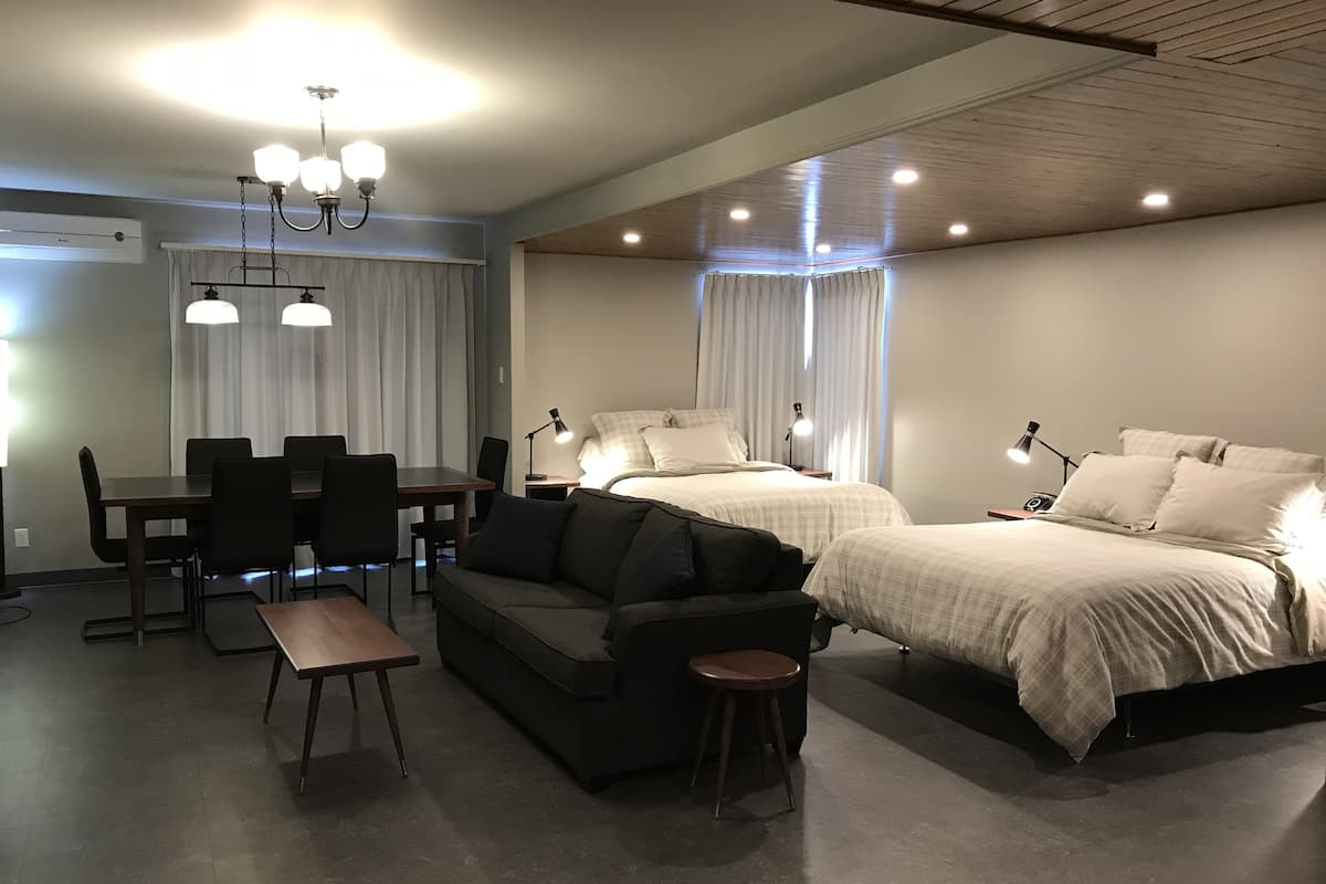 Une chambre d’hôtel moderne comprenant un coin repas, un canapé, deux lits et un bureau.