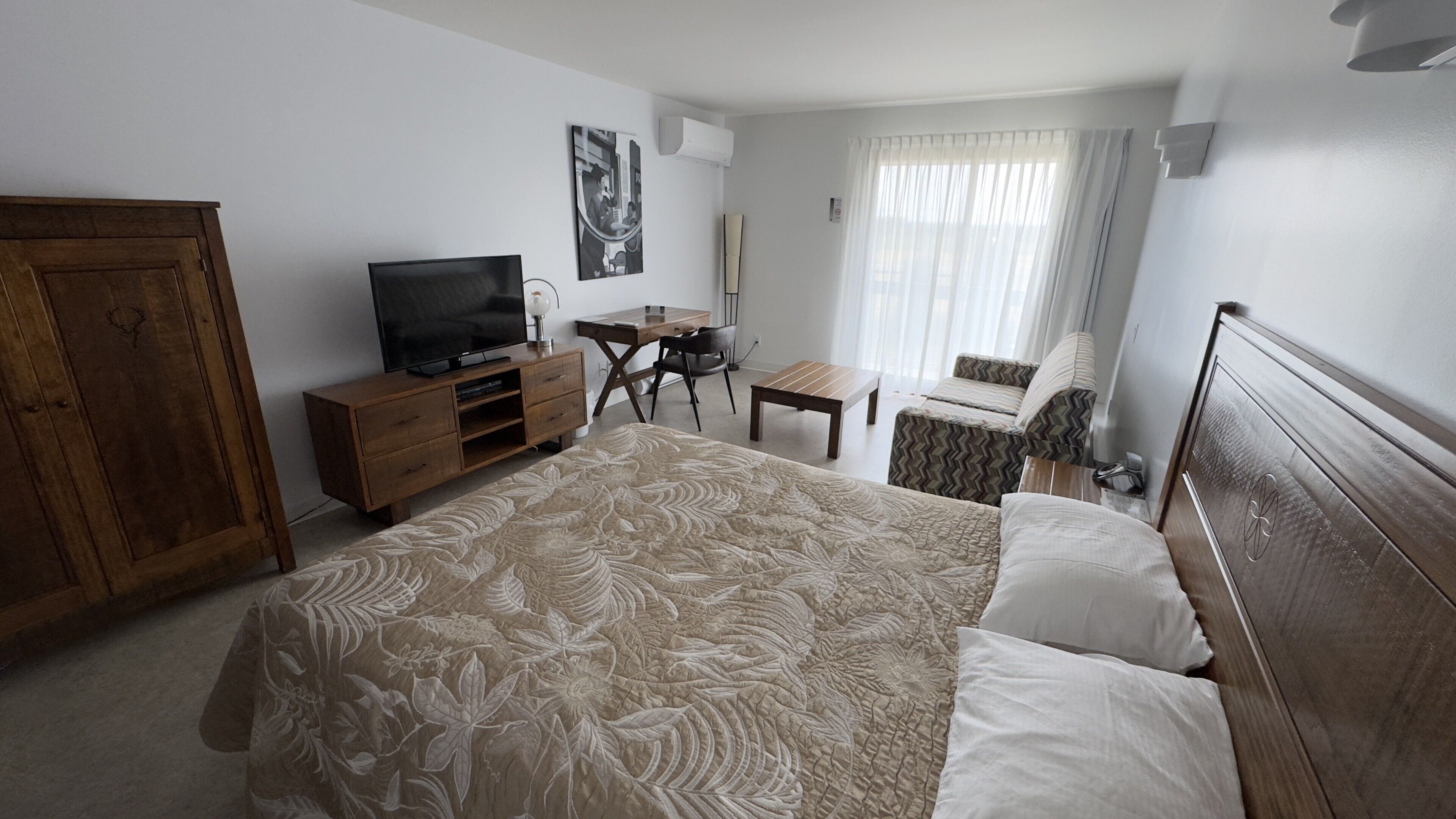 Ett hotellrum med en säng, en tv, ett skrivbord och en stol.