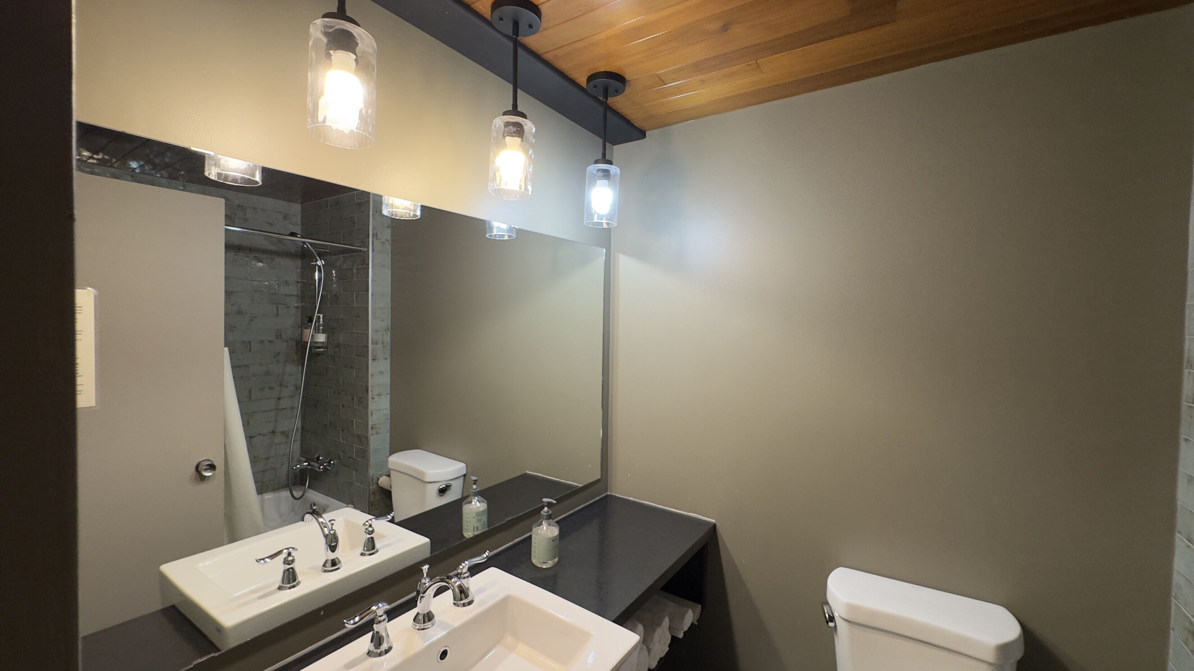 A bathroom with a white sink, a mirror, a toilet, and a shower.