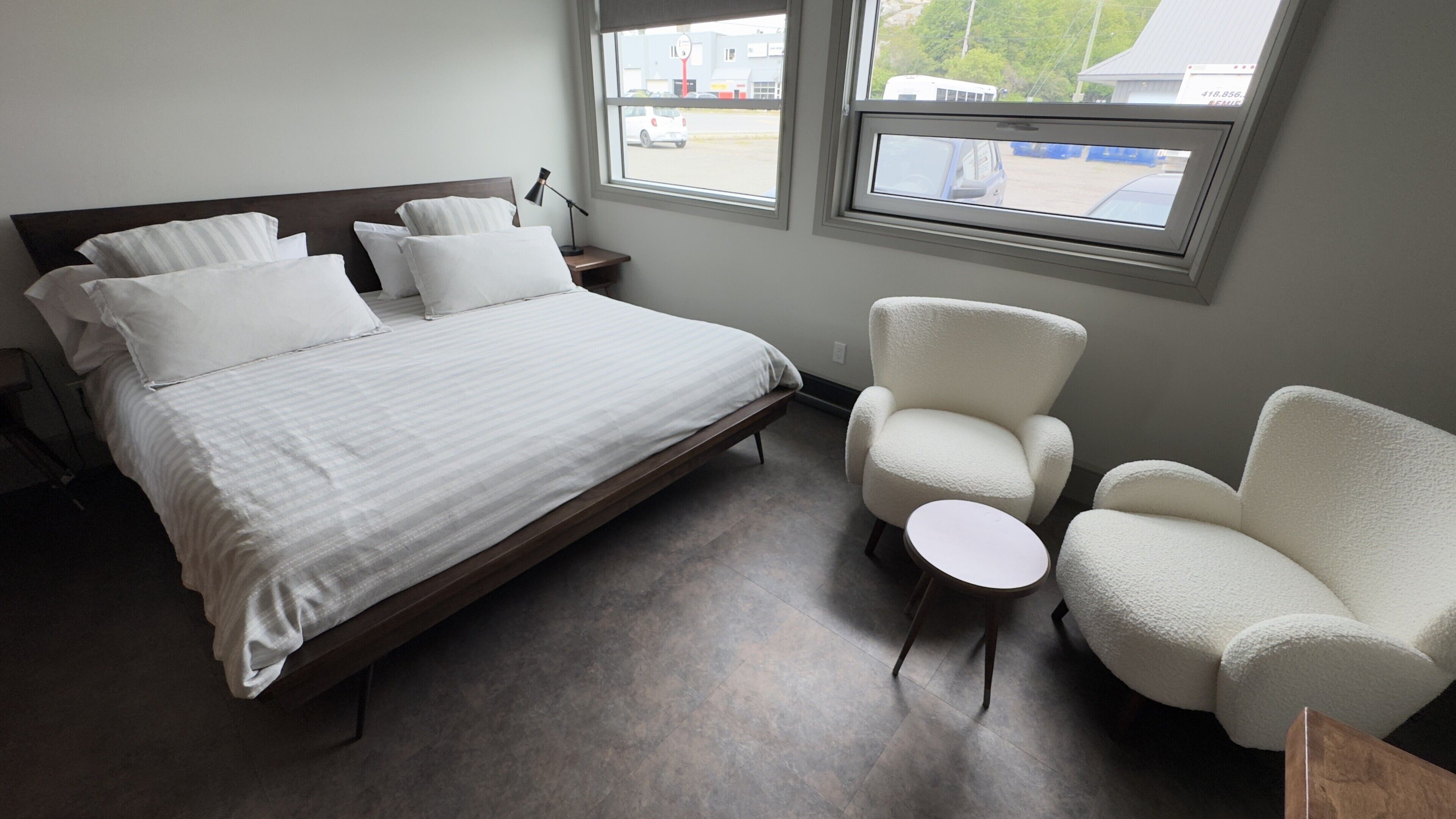 Un dormitorio con cama, dos sillas, una mesita y una ventana con vistas al exterior.