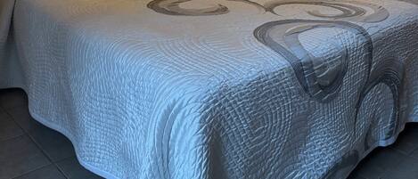 Quarto de hotel com duas camas, cada uma com cabeceira e mesa de cabeceira.