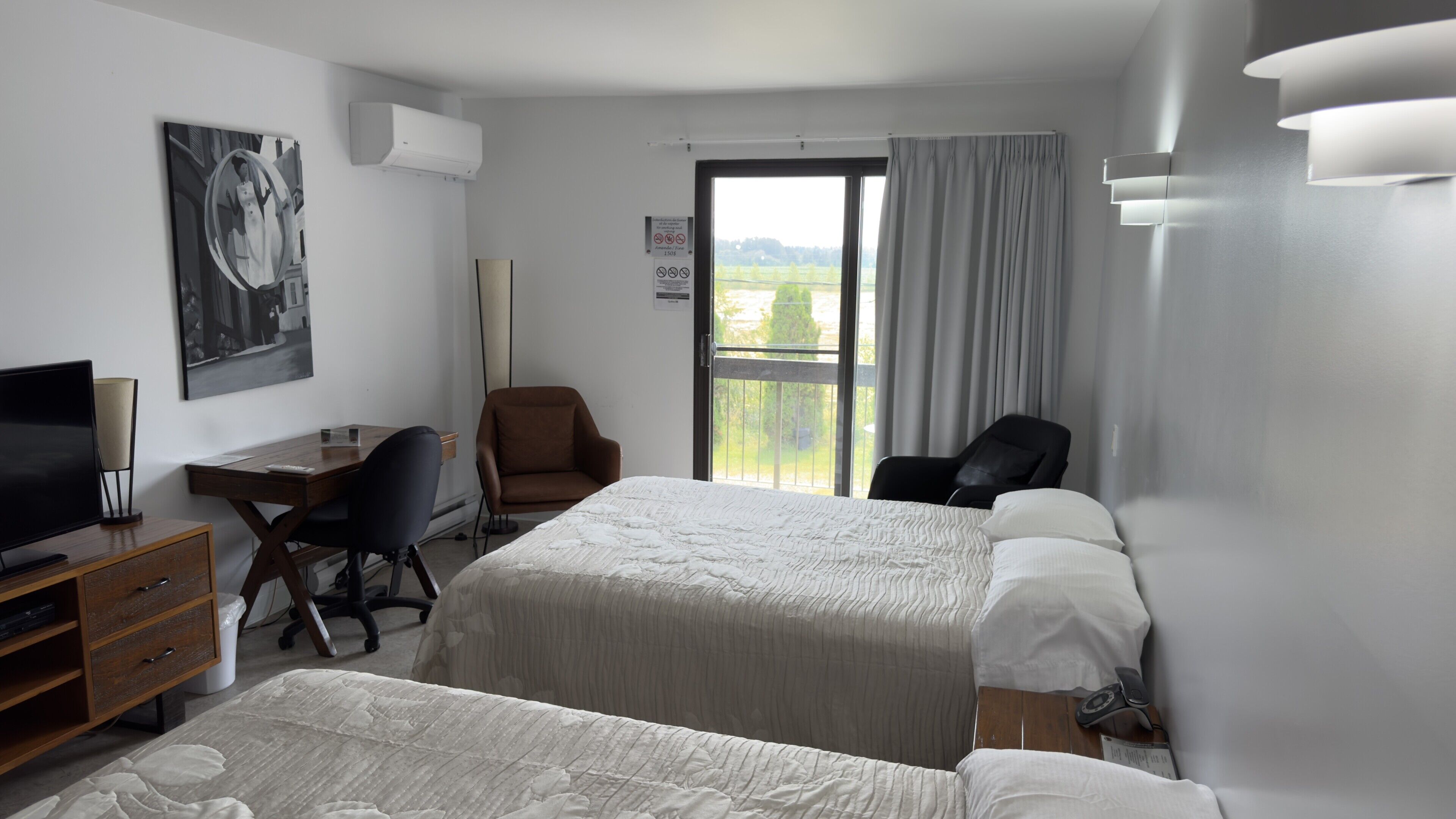 A hotel room with a bed, a desk, a chair, a television, and a window with a view.