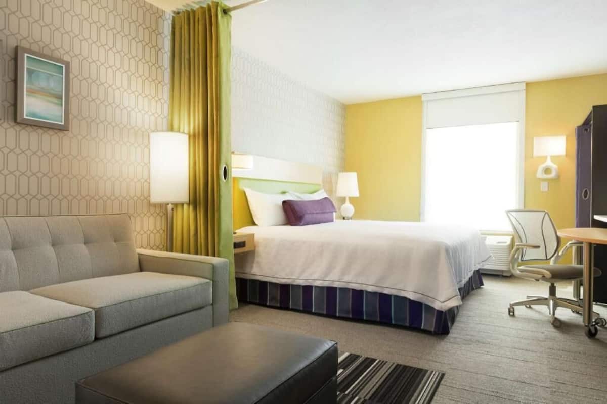 Ein Hotelzimmer mit Bett, Sofa, Schreibtisch und Stuhl.