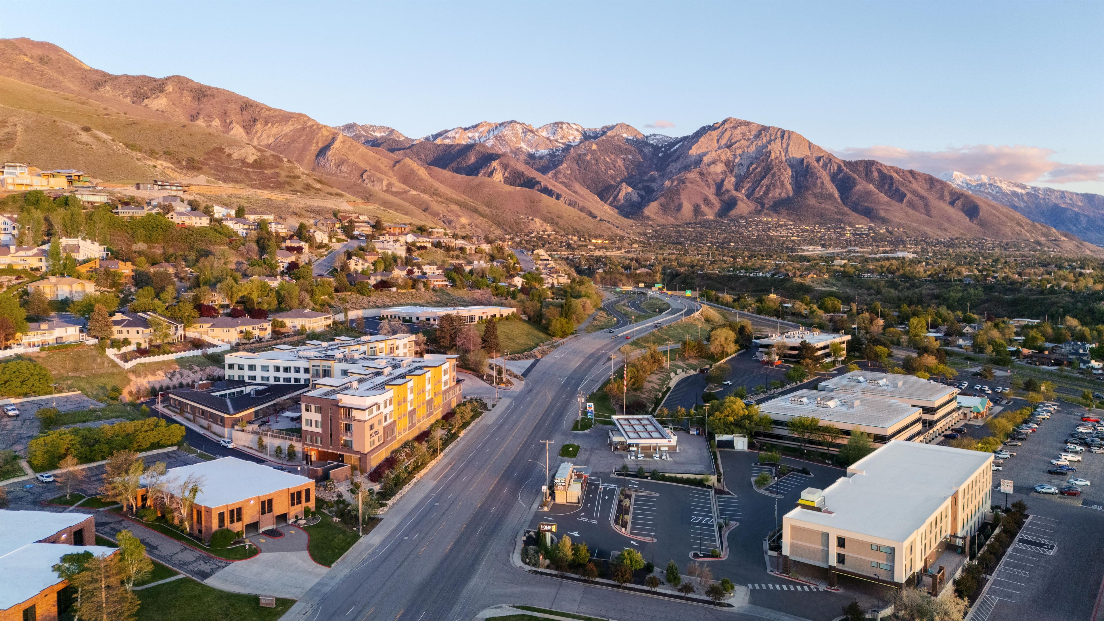 A town with a main road, buildings, and mountains in the background.