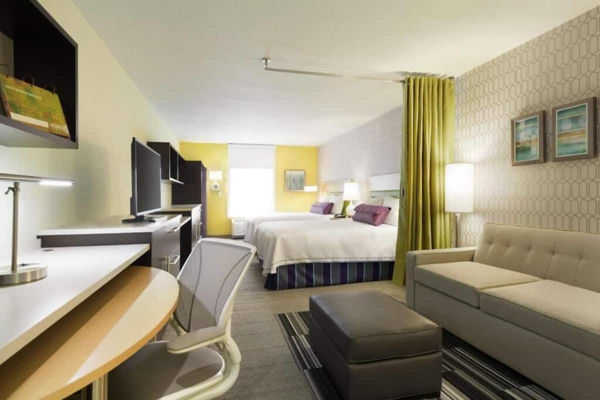 Ein Hotelzimmer mit Bett, Schreibtisch, Stuhl, Sofa und Fernseher.
