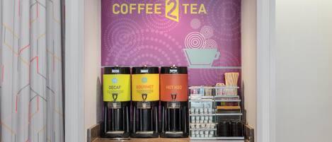 A coffee and tea station with three dispensers labeled 'Decaf,' 'Gourmet,' and 'Hot H2O,' and a mug rack below.
