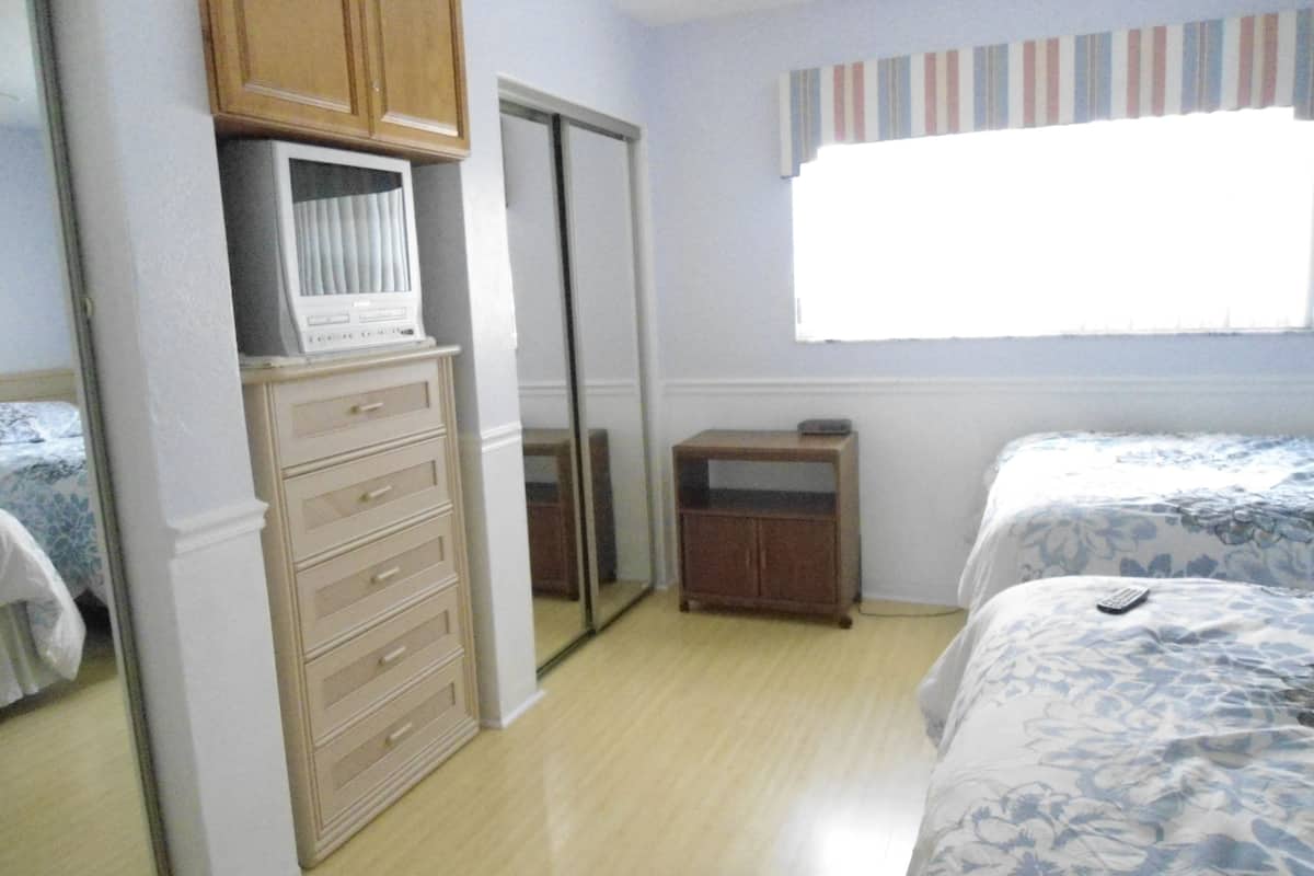 Ein Schlafzimmer mit Bett, Kommode, Kleiderschrank und einem Fenster mit Vorhängen.