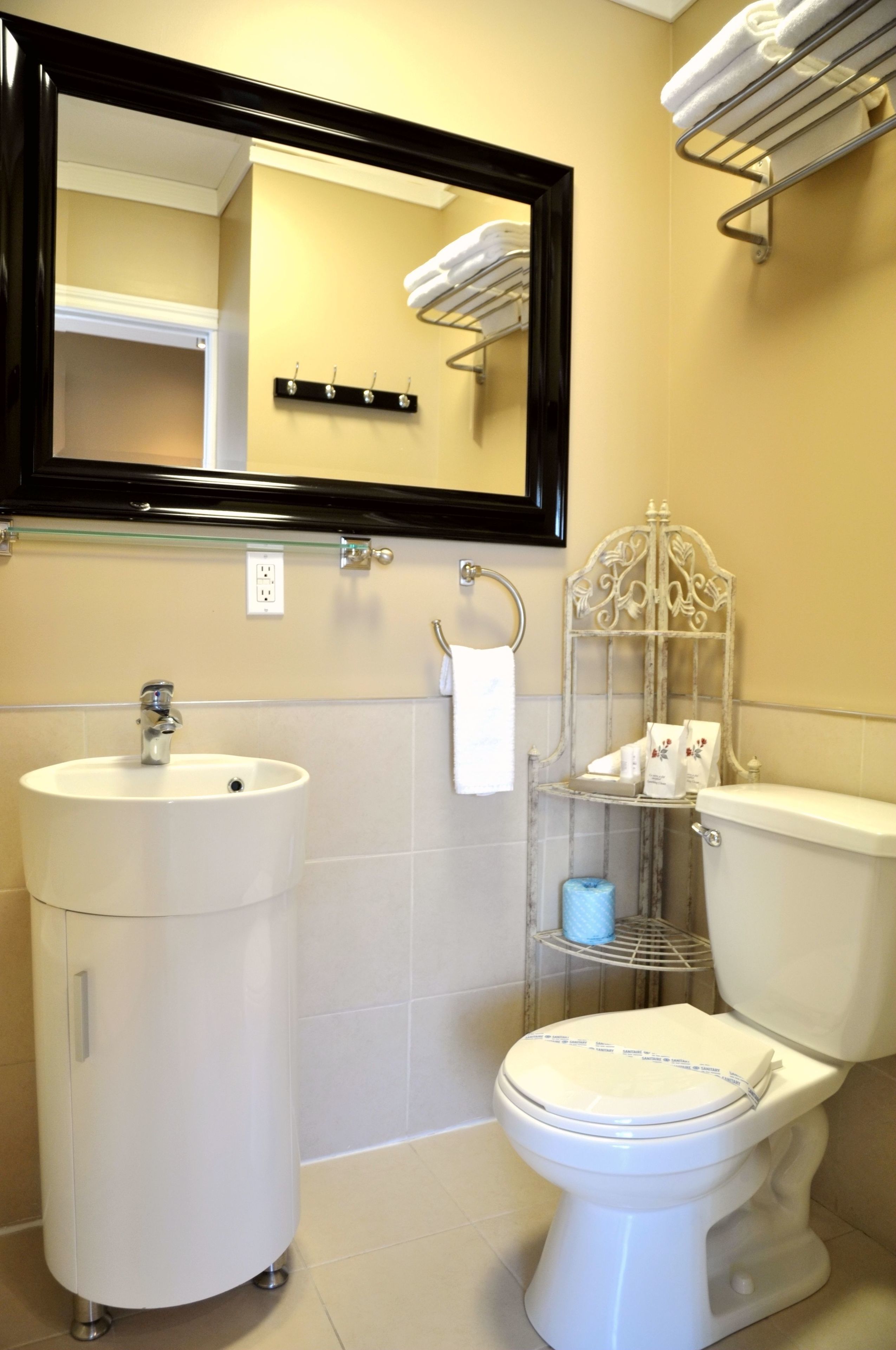 A bathroom with a white sink, toilet, and a mirror above the sink.