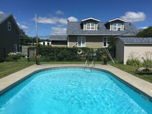 A rectangular swimming pool with a ladder leading into it, surrounded by a grassy area and a fence. - Motel des Cèdres (Sherbrooke)