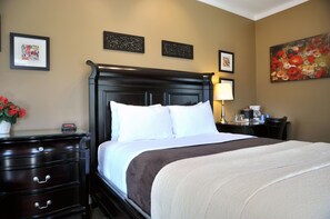 A hotel room with a large bed, a dresser with drawers, a nightstand with a lamp, and framed artwork on the walls. - Motel des Cèdres (Sherbrooke)
