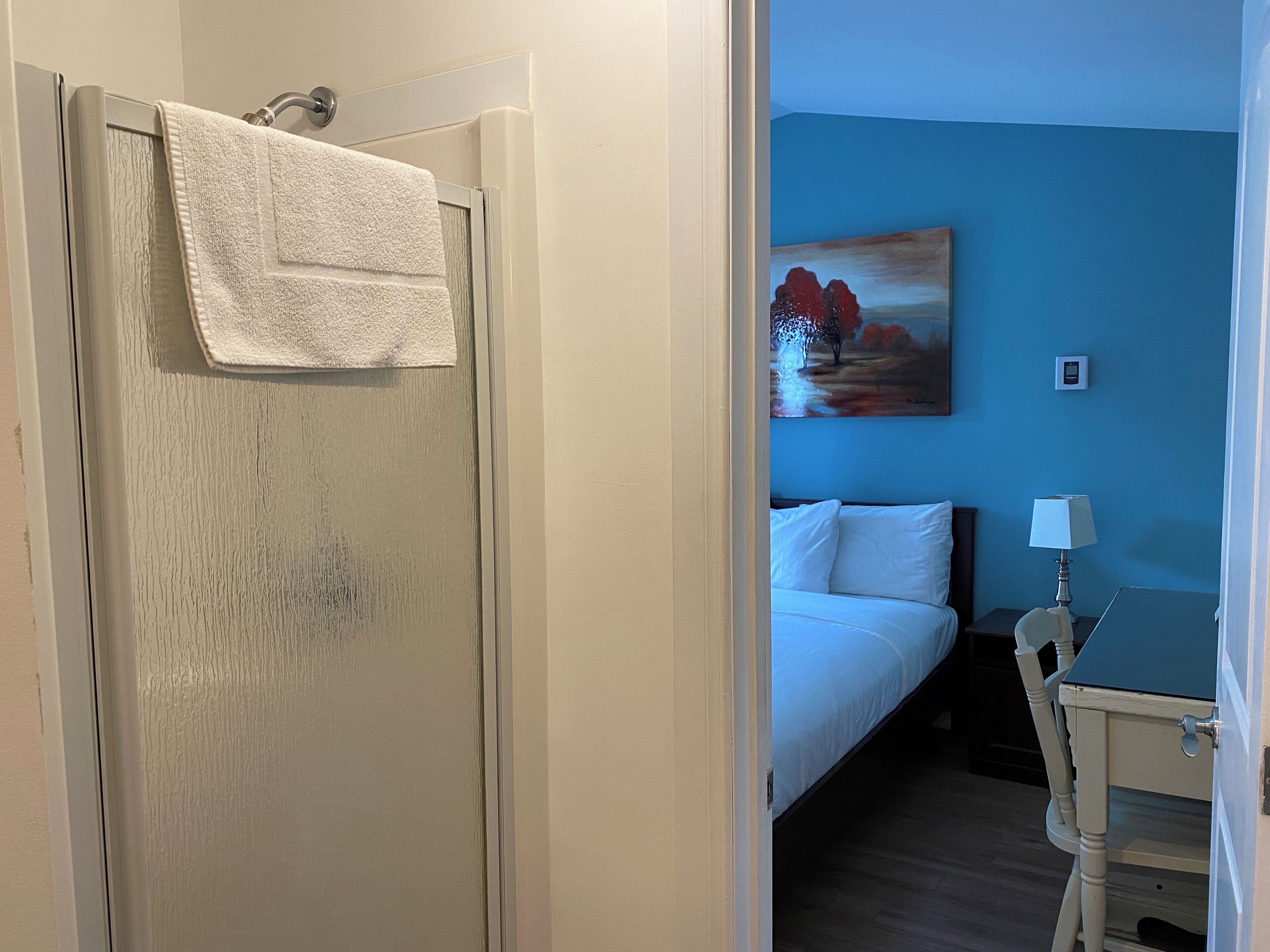 Una habitación de hotel con una cama, un cuadro en la pared, un escritorio y una silla.