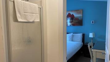 Una habitación de hotel con una cama, un cuadro en la pared, un escritorio y una silla.