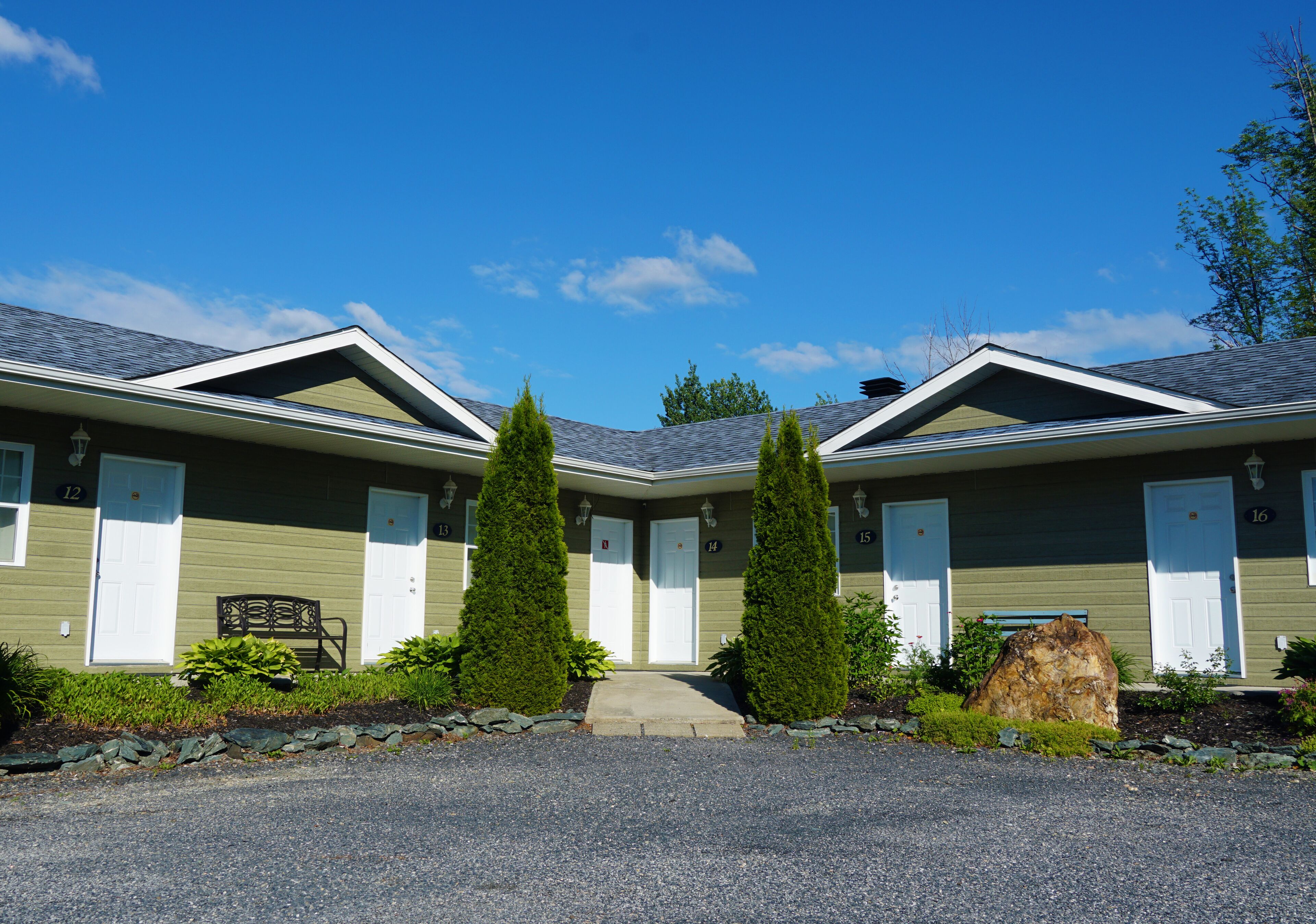 A row of two-story buildings with a gravel driveway and a pathway leading to the entrance.
